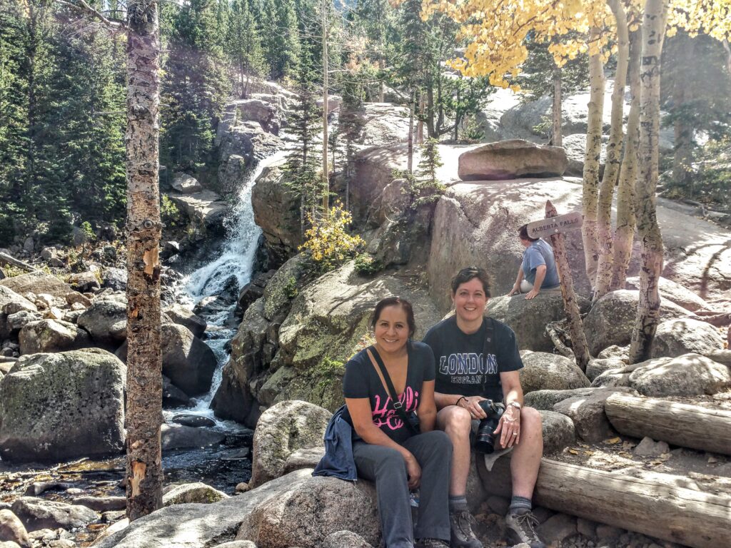 Two women sitting beside Alberta Falls in Rocky Mountain National Park