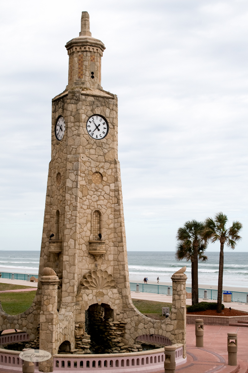 The Daytona Beach Florida clock tower with palm trees and the ocean in the background.