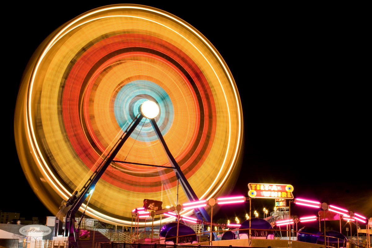 A slow motion image of a ferris wheel, taken at night with the lights on on Daytona Beach Florida.