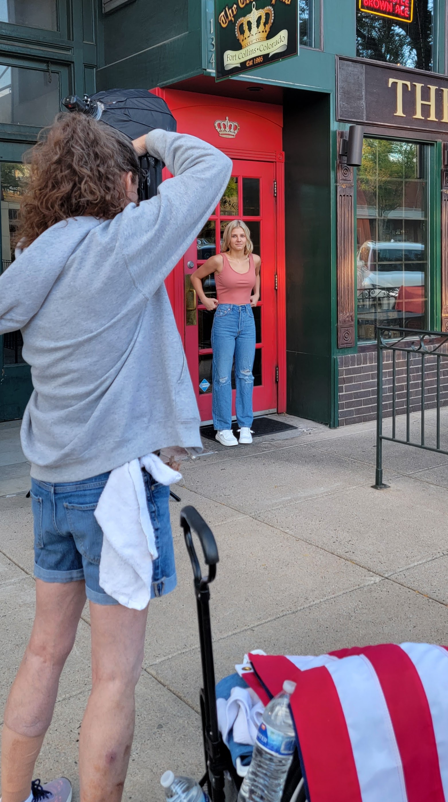 Behind the scenes of a high school senior girl getting photographed against a red door in fort collins by Carol Dunnigan Photography.