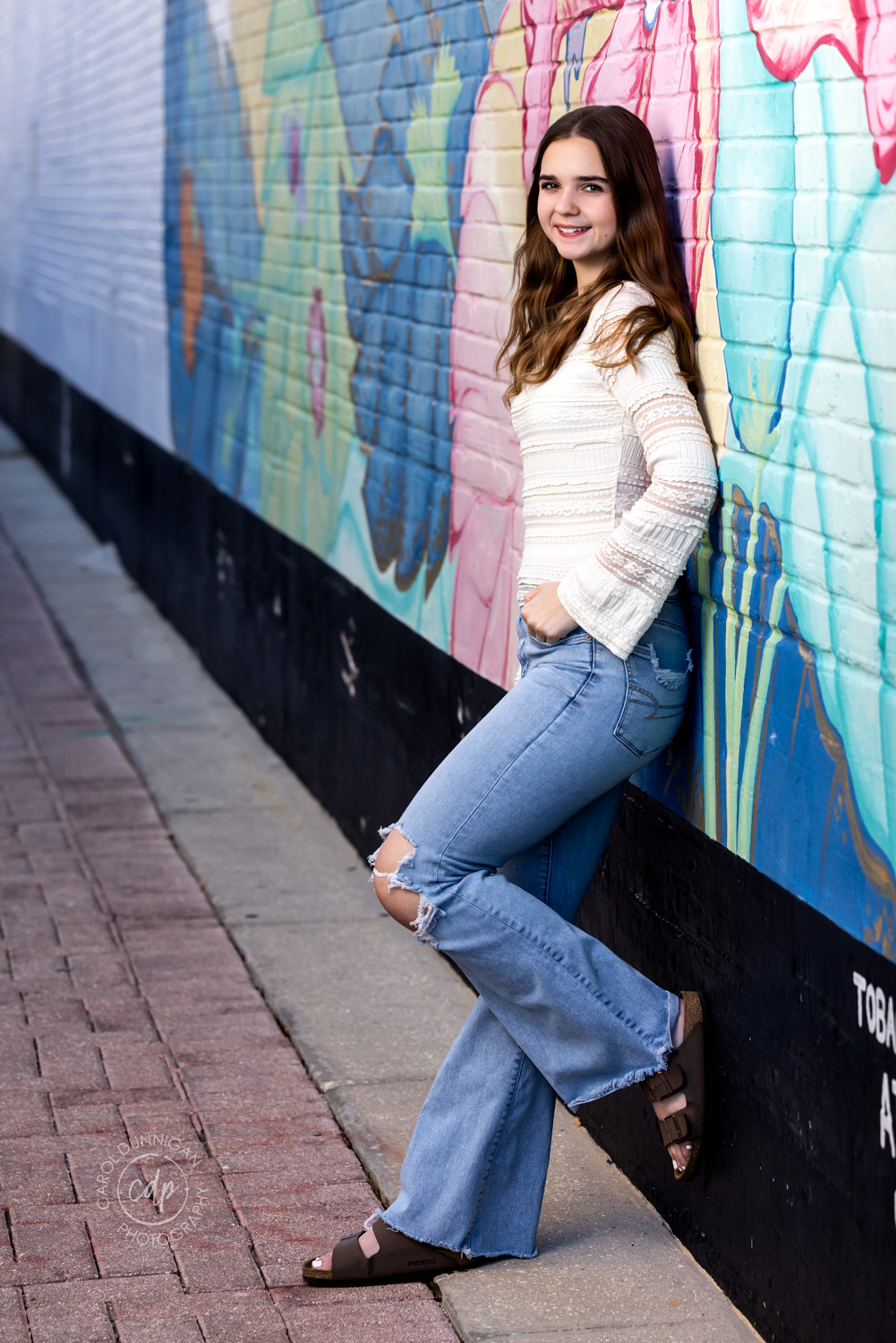 high school senior girl leaning against a graffiti wall having one foot on the wall during her senior session with carol dunnigan photography
