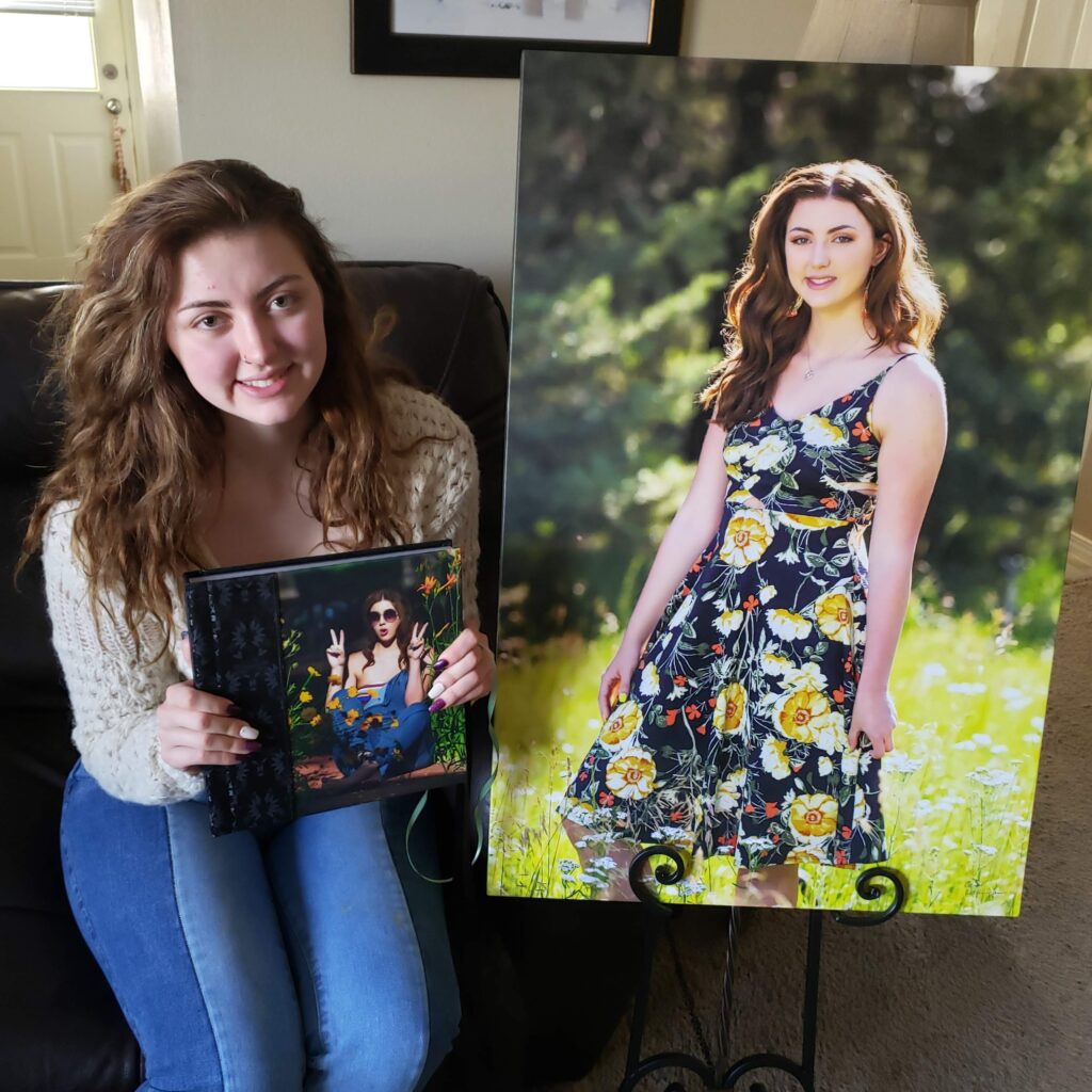 High school senior holding a custom canvas and heirloom album from her senior portrait session.