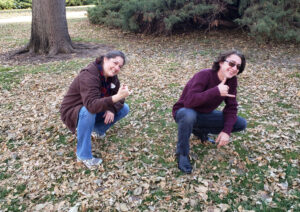Behind-the-scenes of Carol Dunnigan Photography and a high school senior both making a hang 10 sign with their fingers and they're squatting in Greeley Colorado.