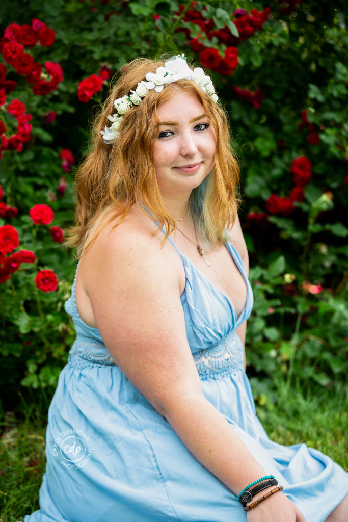 Cassie posing among roses at the CSU Flower Trial Garden in Fort Collins during her senior portrait session