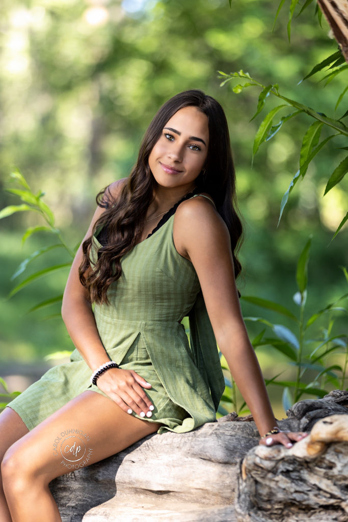 Jada sitting on a log at River's Edge Natural Area during her senior portrait session