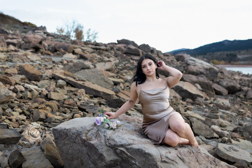 Jayna posing among the rocks with Horsetooth Reservoir and the mountains behind her during her senior portrait session
