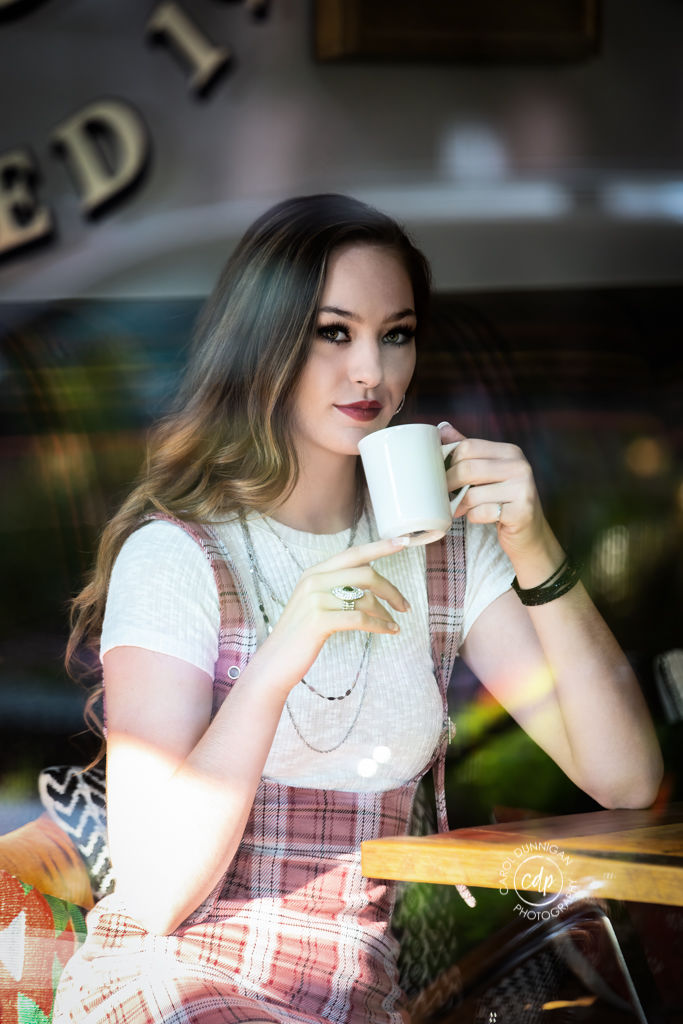 Maddie sitting outside a coffee shop in Old Town Fort Collins during her senior portrait session