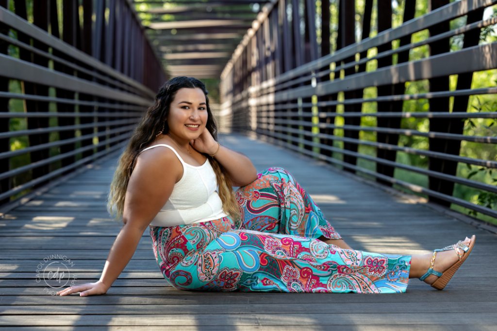 Sophia sitting on a bridge at Lions Open Space in LaPorte during her senior portrait session