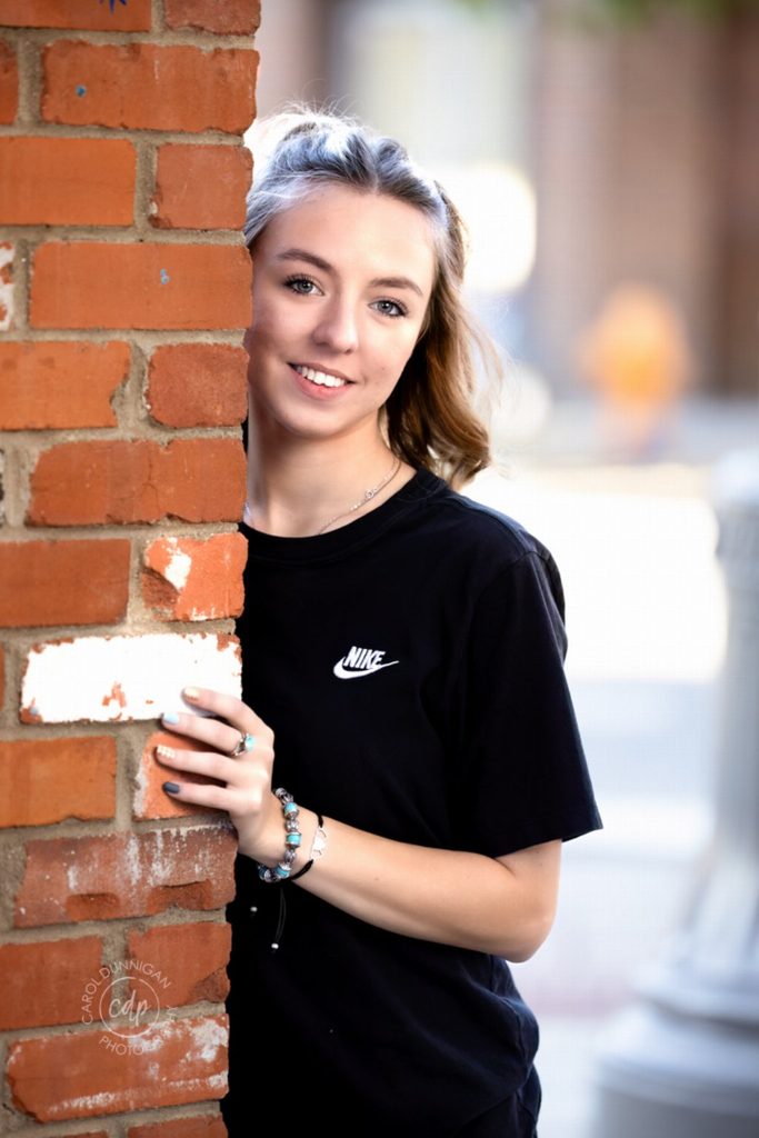 Demy posing against a brick wall during her downtown Loveland senior pictures