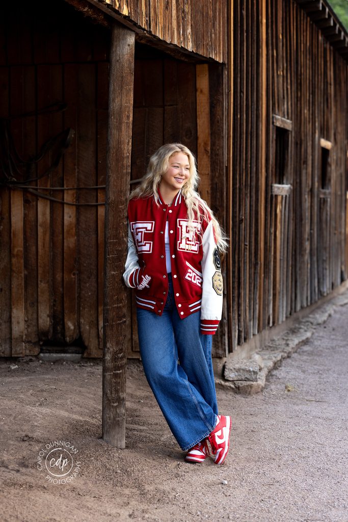 Jayda wearing a letterman jacket and sneakers during her senior pictures near Loveland, Colorado