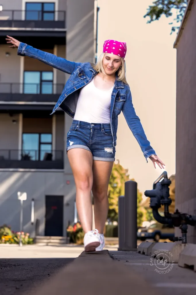 Juliaunna walking on a curb with arms out in downtown Loveland during her senior portrait session