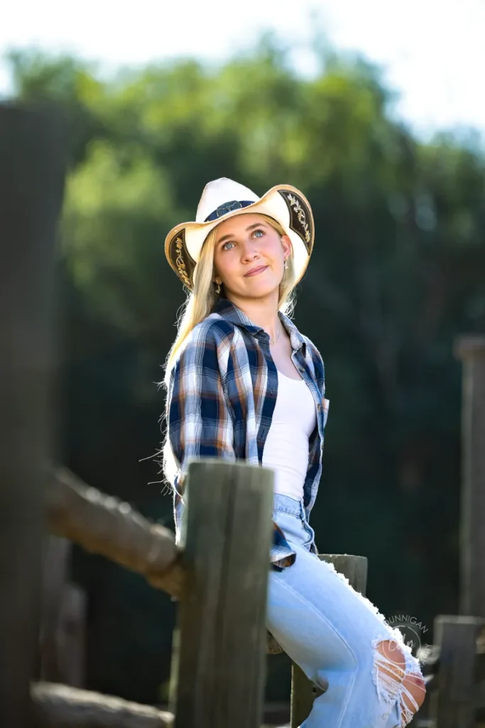 Juliaunna sitting on a fence during her Colorado senior portrait session near Loveland