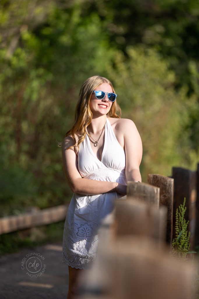 High school senior wearing sunglasses and smiling during her Lyons, Colorado senior portrait session