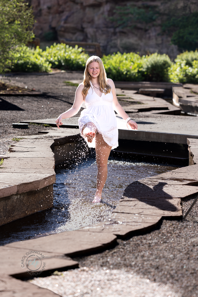 High school senior kicking the water in Lyons, Colorado during her senior portrait session