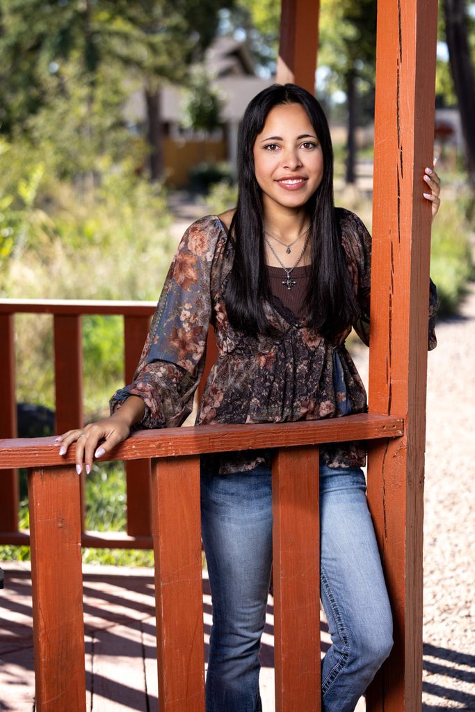 Senior girl wearing a floral top and jeans posing for a yearbook portrait in Greeley.