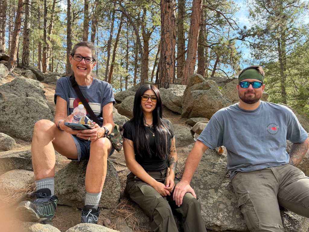 Three hikers taking a break on large rocks along the Anne U. White Trail