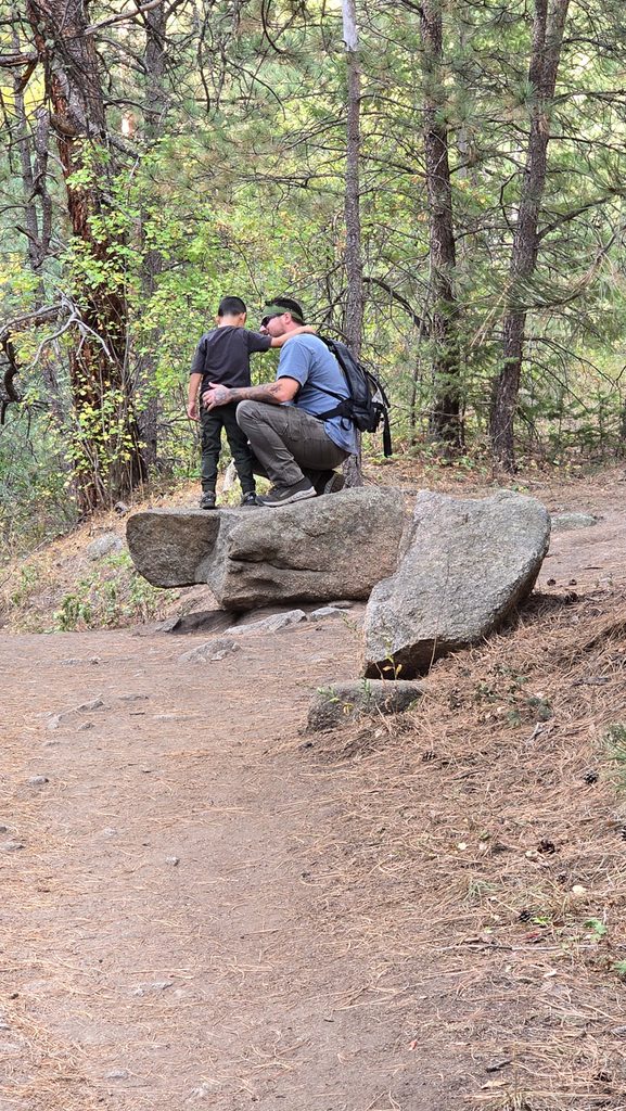 Father and son hikers taking a break on large rocks along the Anne U. White Trail